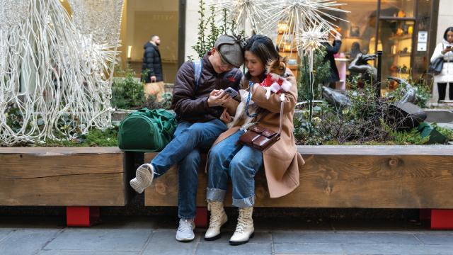 A couple sits on a bench with their dog at Rockefeller Center during the 2021 holiday season in New York City. (Alexi Rosenfeld/Getty Images)