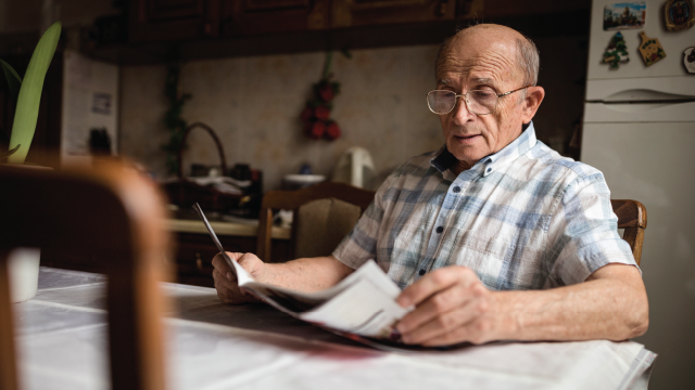 Senior man reading daily newspapers at home