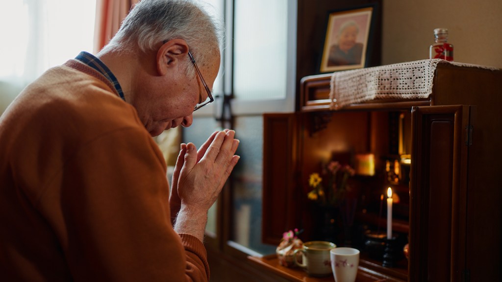 Photo showing Japanese man at his Buddhist family altar, or butsudan.