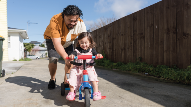 An image a Pacific Islander man teaching his daughter how to ride a bike (nazar_ab via Getty Images)