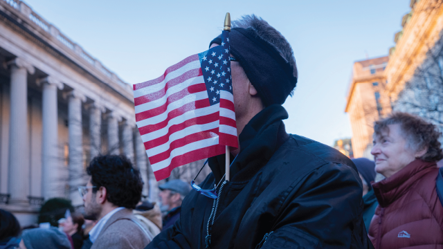 A demonstrator stands with an American flag planted in his coat during a protest in front of the U.S. Treasury Department in Washington, D.C., on Feb. 4, 2025. (Hossein Fatemi/Middle East Images/AFP via Getty Images)