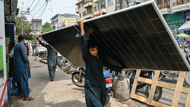 A worker carries a solar panel in Karachi, Pakistan, on June 23, 2025. (Asif Hassan/AFP via Getty Images)