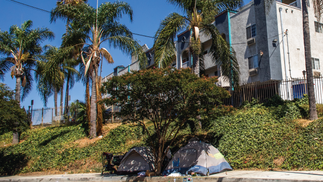 Image shows An encampment of homeless people is seen next to a residential building in Los Angeles on July 25, 2025. (Apu Gomes/Getty Images)